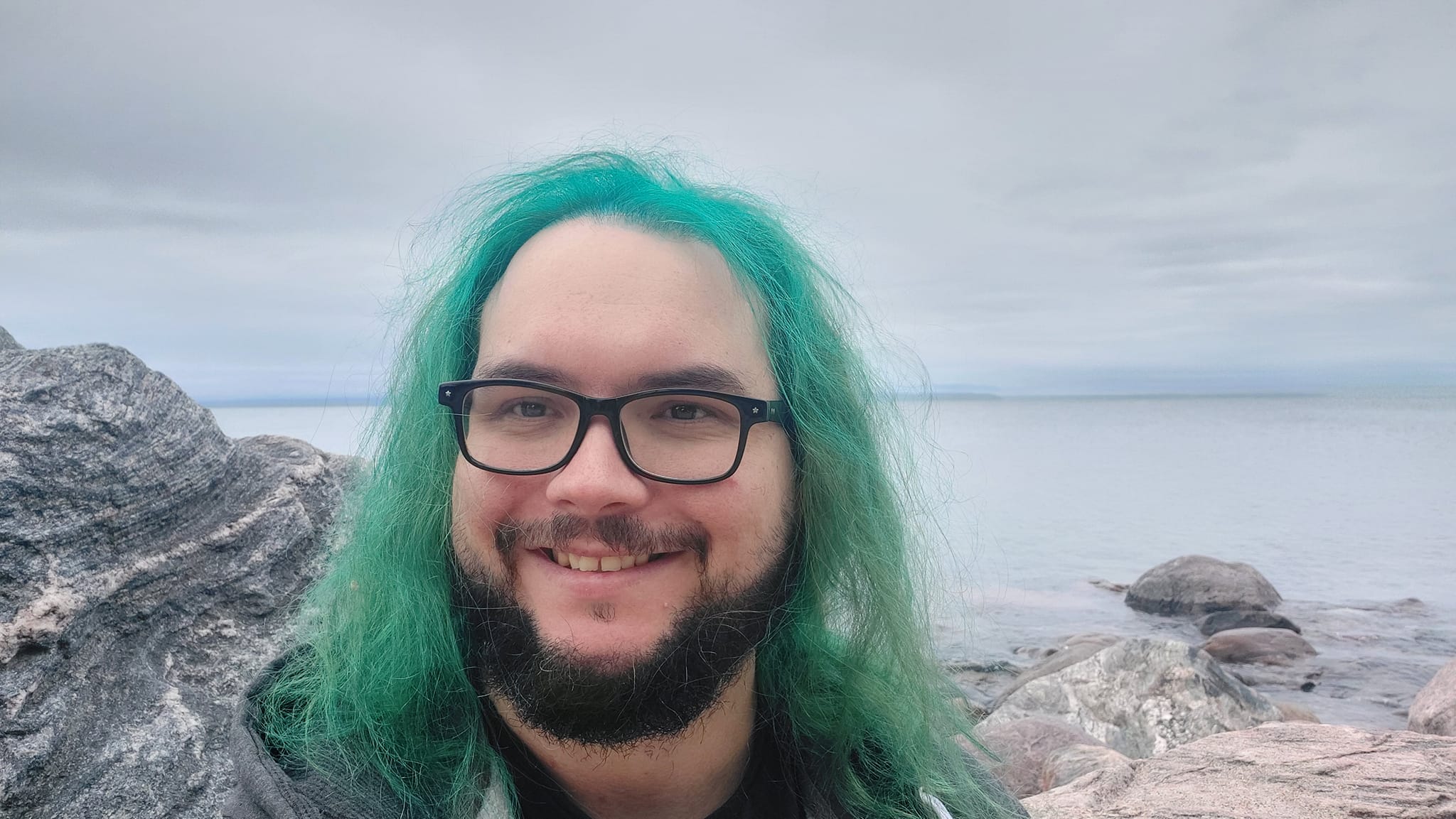 A man with green hair stands outside at a boulder breakwater, photo 16